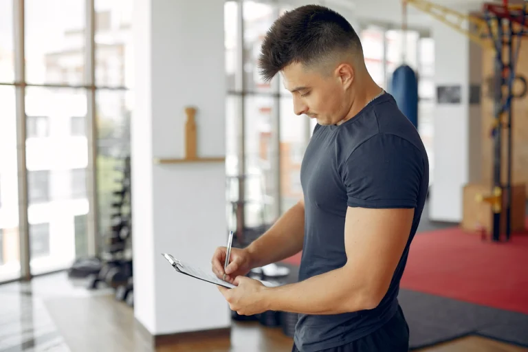 Person planning gym workout schedule in calendar with exercise routine and time slots marked